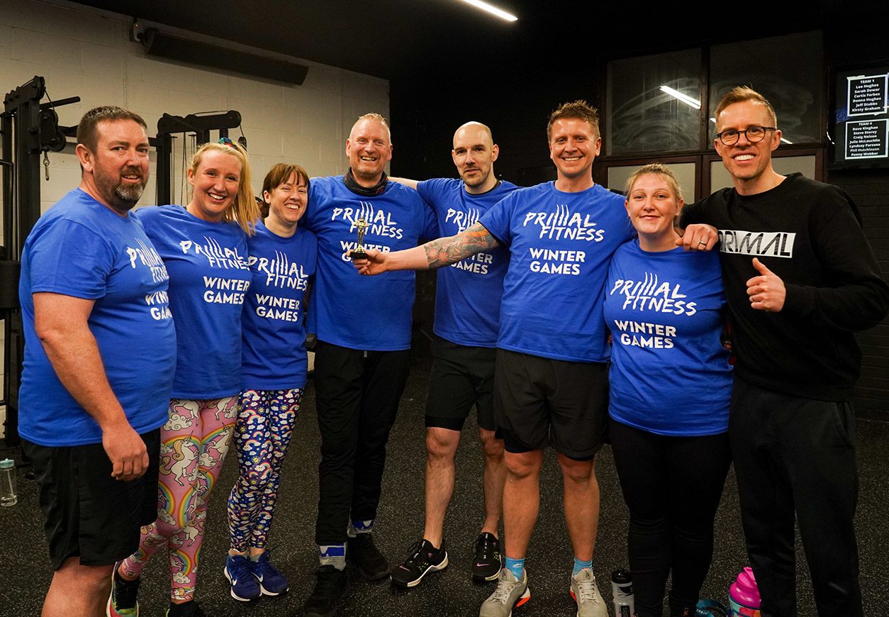 Primal members in Winter Games tees, arms round each other