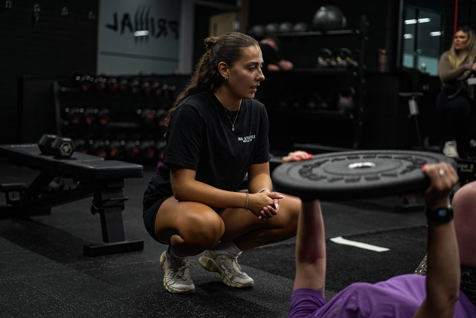 A Primal member crouched with a weight plate on the gym floor